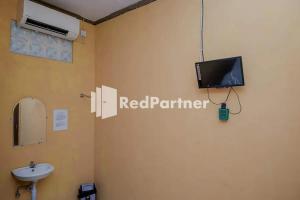 a bathroom with a sink and a tv on the wall at Pondok Damai Guest House Syariah Mitra RedDoorz in Cirebon