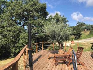 una terraza de madera con 2 sillas y una mesa en Maison ronde atypique en bois, en Carmaux