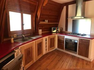 cocina con armarios de madera, fregadero y fogones en Maison ronde atypique en bois, en Carmaux