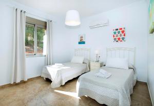 a white bedroom with two beds and a window at El Tajaral in El Gastor