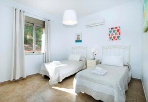a white bedroom with two beds and a window at El Tajaral by Vintage Travel in El Gastor