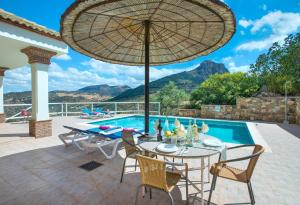 a patio with a table and chairs and an umbrella at El Tajaral by Vintage Travel in El Gastor