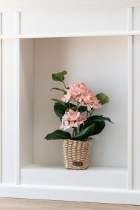 a basket of pink flowers sitting on a shelf at White Elegance Apartment with AC & FREE GARAGE by Renters in Poznań