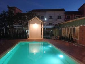 una piscina di fronte a un edificio di notte di casa coco residence a Nakhon Ratchasima
