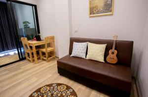 un soggiorno con divano marrone e chitarra di casa coco residence a Nakhon Ratchasima