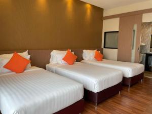 three beds with orange pillows in a room at Tonaoi Grand Hotel in Hat Yai