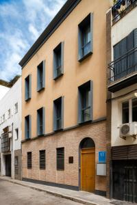 ein Backsteingebäude mit einer braunen Tür auf einer Straße in der Unterkunft Suites Maestranza - Herrería by Magno Apartments in Sevilla