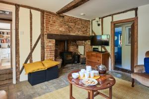 een woonkamer met een tafel en een open haard bij Church Cottage in Halesworth