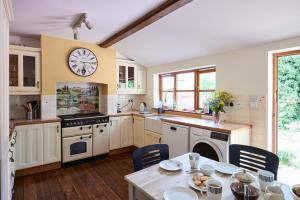 a kitchen with a table and a clock on the wall at Church Cottage in Halesworth +14 photos