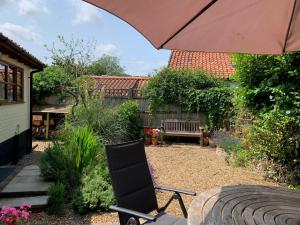 a patio with a chair and an umbrella at Church Cottage in Halesworth