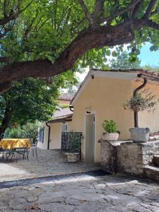 a house with a table and chairs and a tree at Les Deux Tilleuls in Sablet