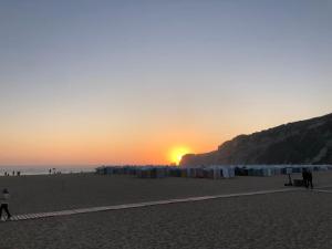 einen Strand mit Sonnenuntergang in der Ferne in der Unterkunft Casa dos Pexins Buzina Sitio in Nazaré