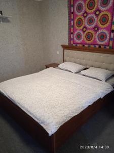 a bed in a bedroom with a painting on the wall at Гостевой дом AL XALIL in Samarkand