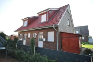 una casa con techo rojo y garaje en Nr 137 - Ferienhaus In't Seeburger Winkel, en Carolinensiel