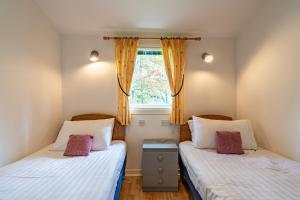 two twin beds in a room with a window at Heather Lodge 3 with Hot Tub in Belladrum