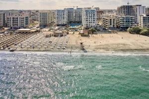 a beach with umbrellas and a beach with buildings at Infinity Breezes Apartment Beach Resort - parking in Mamaia