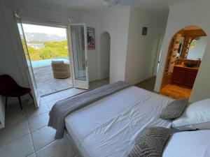 ポルト・ヴェッキオにあるVilla Bianca - Vue imprenable Mer & Porto-Vecchio, Piscine chauffée à débordement, Accès privé plageのベッドルーム1室(ベッド1台付)、スライド式ガラスドアが備わります。