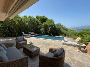 un patio avec des chaises et une piscine dans l'établissement Villa Bianca - Vue imprenable Mer & Porto-Vecchio, Piscine chauffée à débordement, Accès privé plage, à Porto-Vecchio