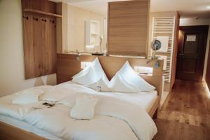 ein Schlafzimmer mit einem großen weißen Bett mit weißen Kissen in der Unterkunft Hotel Goldener Berg in Lech am Arlberg