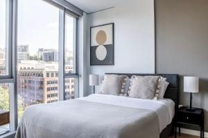 a white bedroom with a large bed and large windows at Pioneer Square studio w gym bbq nr stadium SEA-588 in Seattle