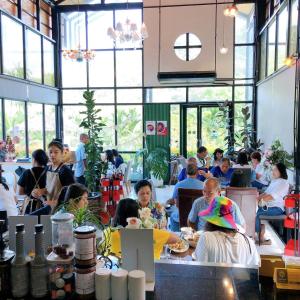 a group of people sitting at tables in a restaurant at คุ้มกะลาหัวฟาร์มสเตย์ (Khumkalahua Farmstay) in Ban Pha Saeng Lang