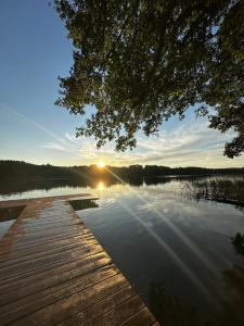 a sunset over a lake with a wooden dock at Przystanek Krag - kazdy domek ma prywatna balie! Do tego wlasna prywatna plaza, pomost, lodka, kajaki, strefa ciszy, darmowy parking, grille , miejsce na ognisko in Krąg
