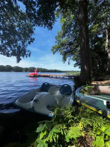 two boats parked on the shore of a lake at Przystanek Krag - kazdy domek ma prywatna balie! Do tego wlasna prywatna plaza, pomost, lodka, kajaki, strefa ciszy, darmowy parking, grille , miejsce na ognisko in Krąg