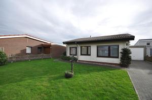 a house with a green lawn in the yard at Nr 201 - Ferienhaus Am Tief in Neuharlingersiel