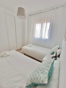 a white room with two beds and a window at SHERRY SUÍTES VI Apartamentos PARKING GRATUITO in Jerez de la Frontera