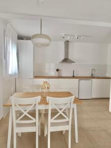 a kitchen with a wooden table and two white chairs at SHERRY VI Apartamentos in Jerez de la Frontera