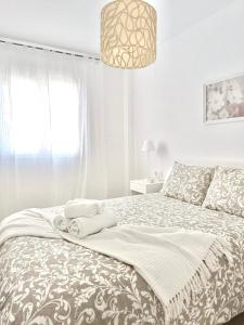 a white bedroom with a bed with a large window at SHERRY SUÍTES VI Apartamentos PARKING GRATUITO in Jerez de la Frontera
