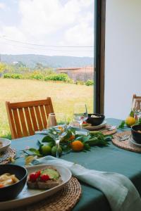 una mesa con platos de comida y copas de vino en Just Like Home Casa da Maria Olívia, en Paredes de Coura