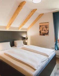 a large white bed in a room with wooden ceilings at MarktlAlm - Superior Waldblick Chalet mit Sauna in Turracher Hohe