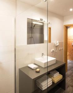 a bathroom with a sink and a glass shower at MarktlAlm - Superior Waldblick Chalet mit Sauna in Turracher Hohe