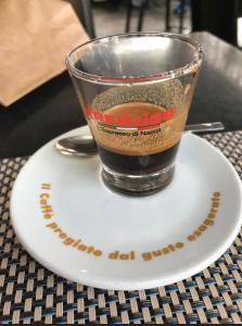 eine Tasse Kaffee auf einem Teller auf einem Tisch in der Unterkunft Suites Caracciolo in Neapel