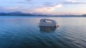 un bateau assis au milieu d'une masse d'eau dans l'établissement Glamping Wallersee - Unter dem Kastanienbaum, à Helming