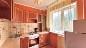 a kitchen with wooden cabinets and a sink and a stove at МАДРИД Апартаменты 2-ком в центре in Petropavlovsk