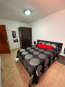 a bedroom with a black and white bed with red pillows at Next to the Sea in Pozo Izquierdo