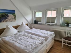 Schlafzimmer mit einem Bett mit weißer Bettwäsche und Fenstern in der Unterkunft Bootshaus, App 4 in Grömitz