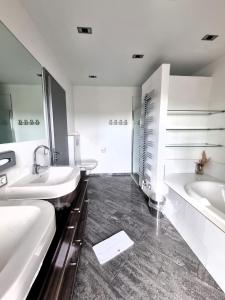 a white bathroom with two sinks and a tub at Mountains and Lakes - Villa Gaumberg in Linz