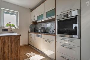 eine Küche mit weißen Schränken und einer Mikrowelle in der Unterkunft Vineyard Cottage Deer's Hill - Happy Rentals in Smarjeske Toplice