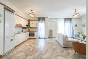 eine große Küche mit weißen Schränken und einer Couch in der Unterkunft Houseloft Kalamaria Highview in Thessaloniki
