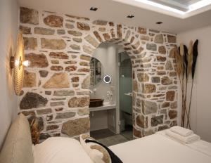 Pokój z kamienną ścianą i łóżkiem w pokoju w obiekcie Annio studios w mieście Plaka