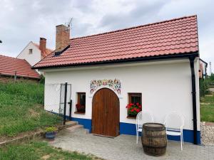una pequeña casa blanca con una puerta de madera y un barril en Vinný sklep S&T Výmola, en Mikulčice