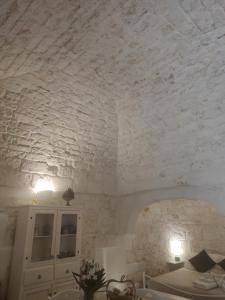 - une chambre avec un mur en briques blanches et un lit dans l'établissement I due cuori, à Ostuni