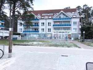 um grande edifício branco com janelas azuis numa rua em Blaumuschel Haus A Wohnung 12 - DH em Lubmin