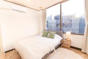 een slaapkamer met een bed en een groot raam bij Meee Asakusa3F4F 浅草徒歩3分 140平米Max22名 無料駐車場 屋上絶景 渋谷直通 in Tokyo