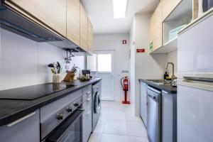 Una cocina con gabinetes blancos y encimeras negras. en Casa Memória, en Vila do Bispo