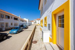 una fila de autos estacionados en una calle al lado de edificios en Casa Memória, en Vila do Bispo