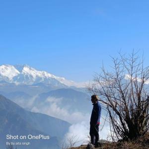 Un homme debout au sommet d'une montagne qui regarde les montagnes dans l'établissement OYO Home Narayan Homestay & Adventures, à Pelling